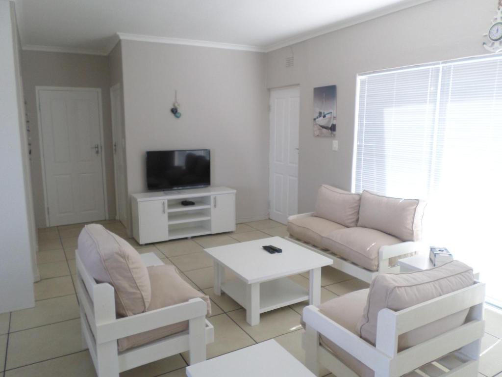 a living room with a couch and a table and a tv at Beach House Bliss in Langebaan