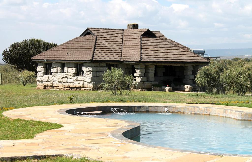 a building with a pond in front of a house at Shwari Cottages in Naivasha