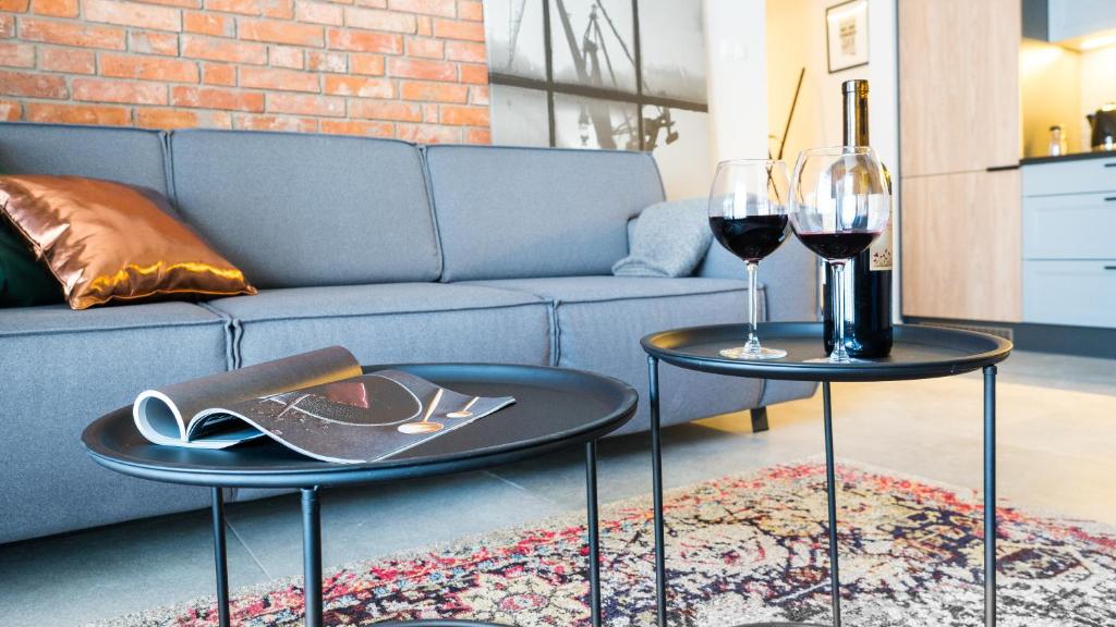 two tables with wine glasses and a couch at City Center - Riverside by Apartmore in Gdańsk