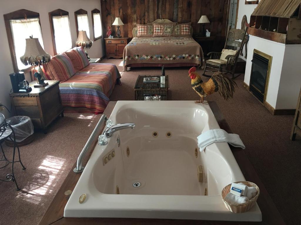 a bathroom with a tub and a living room with a bed at River House Inn in Grassy Creek