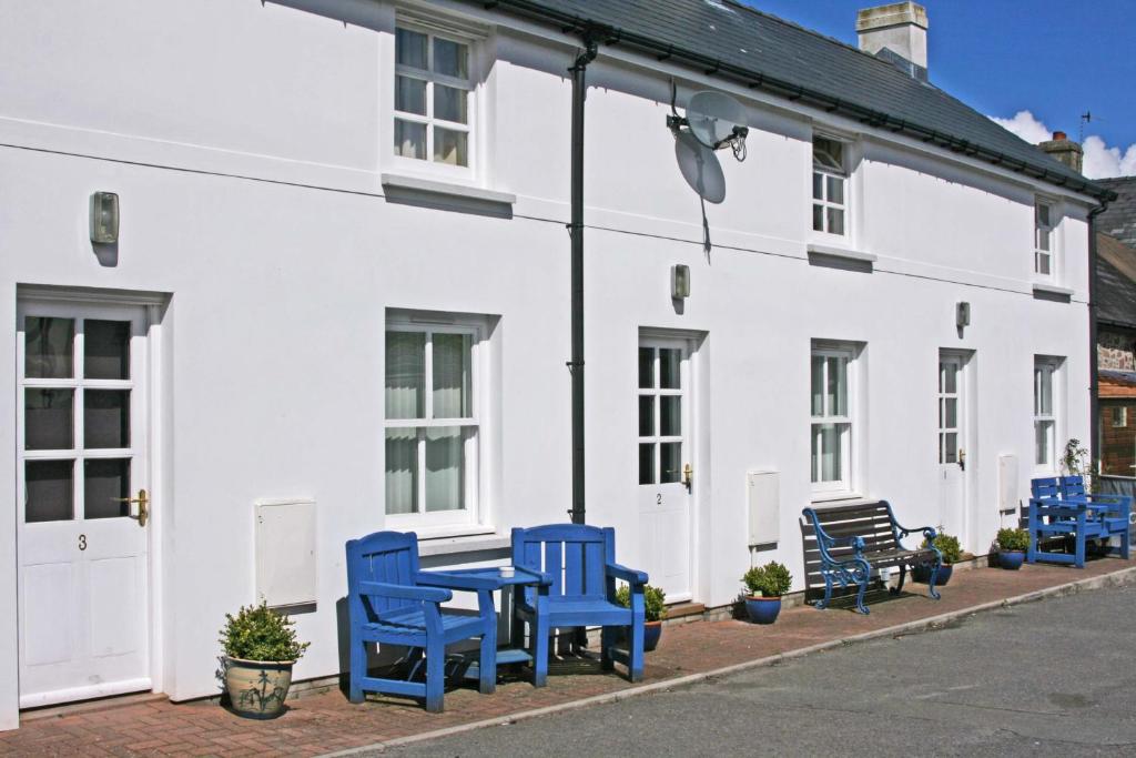um grupo de cadeiras azuis sentado fora de um edifício branco em The Gremlin Lodge em Brecon
