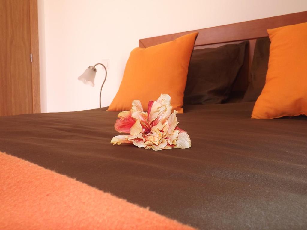 a flower laying on a bed with orange sheets at Maison de l' Épicier in Funchal