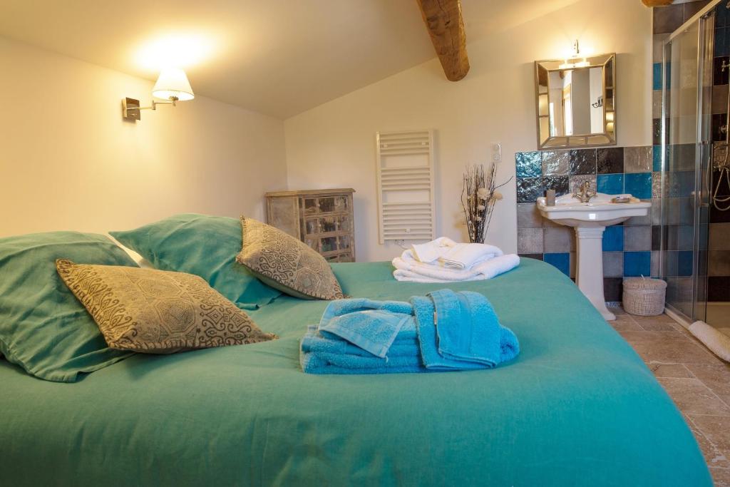 a large green bed with towels and a sink at Mas Du Pont Rouge in Sylvéréal