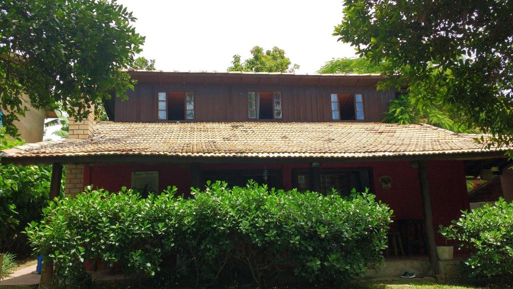 una casa roja con techo rojo y algunos arbustos en Casa Mágica, en Praia do Rosa