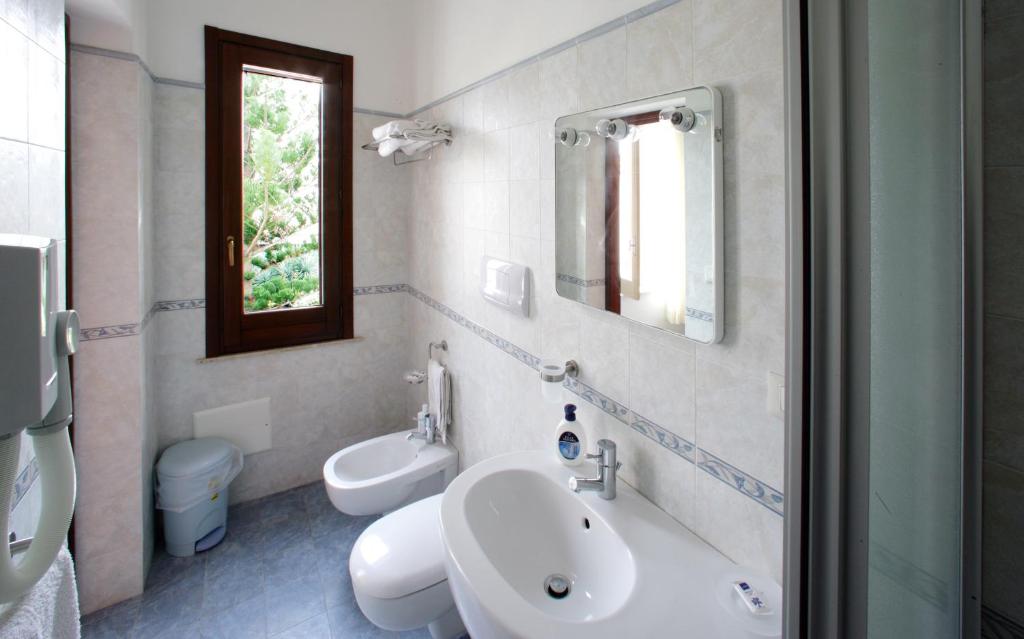 bagno con lavandino, servizi igienici e specchio di Albergo Bouganville a Favignana