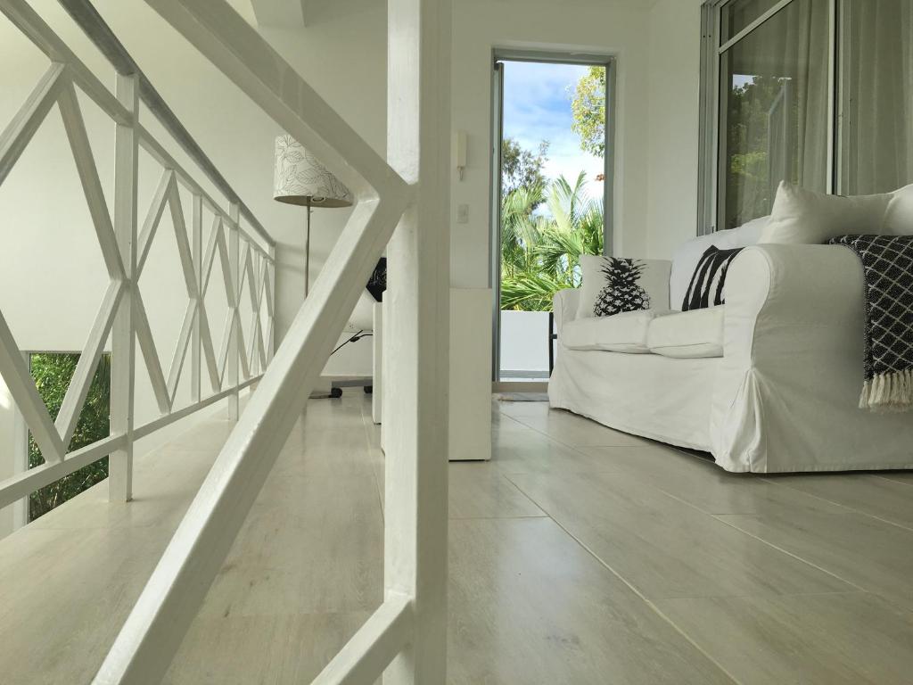 a white bedroom with a bed and a balcony at Casa Veintiuno in Sosúa