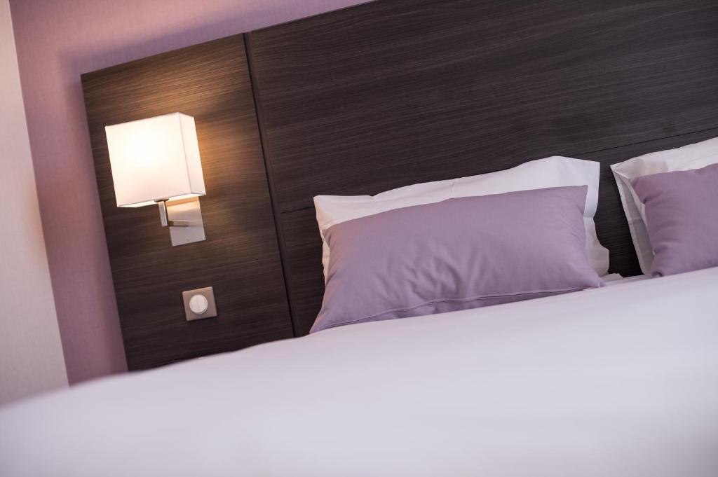 a bedroom with a bed with a headboard and a lamp at Hotel Eurocentre 3* Toulouse Nord in Castelnau-dʼEstrétefonds