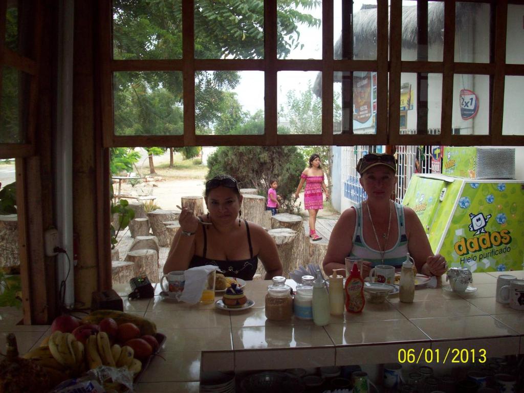 Dos mujeres sentadas en una mesa con un trago en Hostal Camping Beach, en Salinas