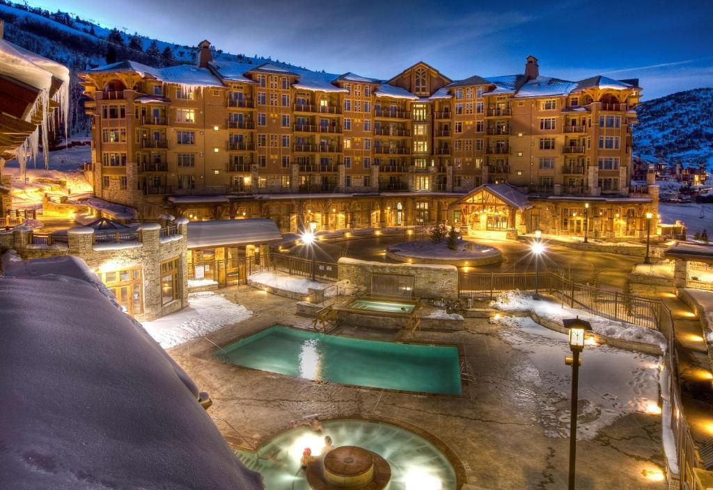a resort with a pool in the snow at night at Hyatt Centric Park City in Park City
