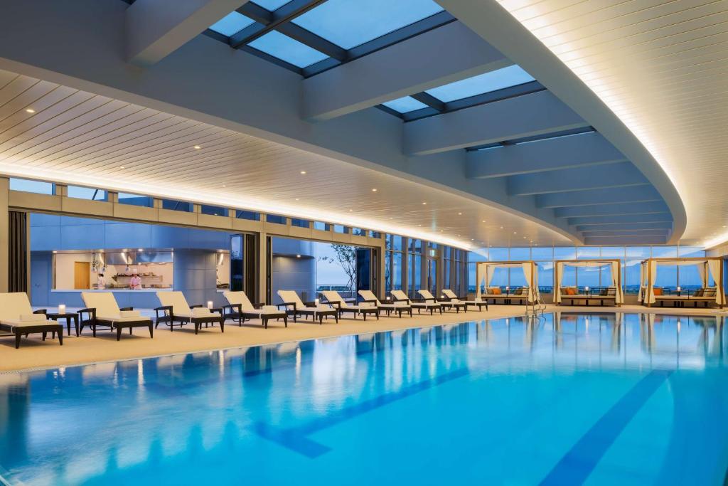 a swimming pool with chairs and tables in a building at Grand Hyatt Incheon in Incheon