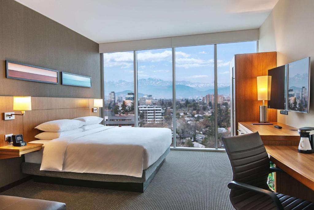 a bedroom with a bed and a desk and a large window at Hyatt Place Santiago/Vitacura in Santiago