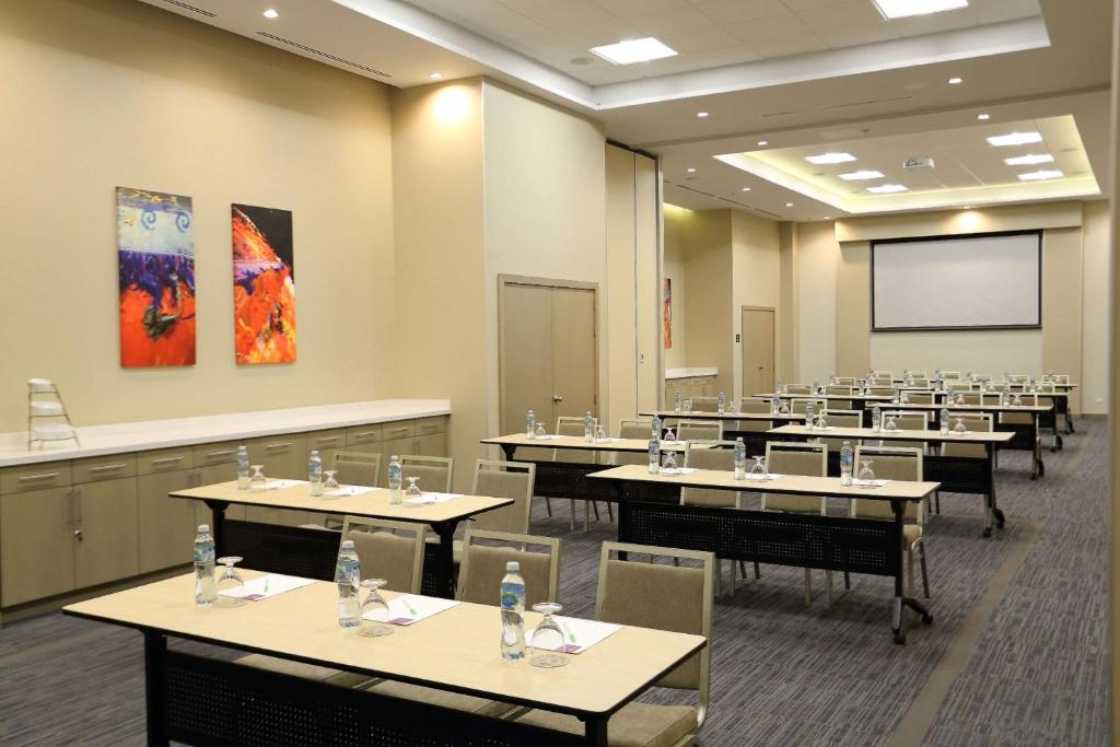 uma sala de aula com mesas e cadeiras e uma tela de projeção em Hyatt Place Tegucigalpa em Tegucigalpa