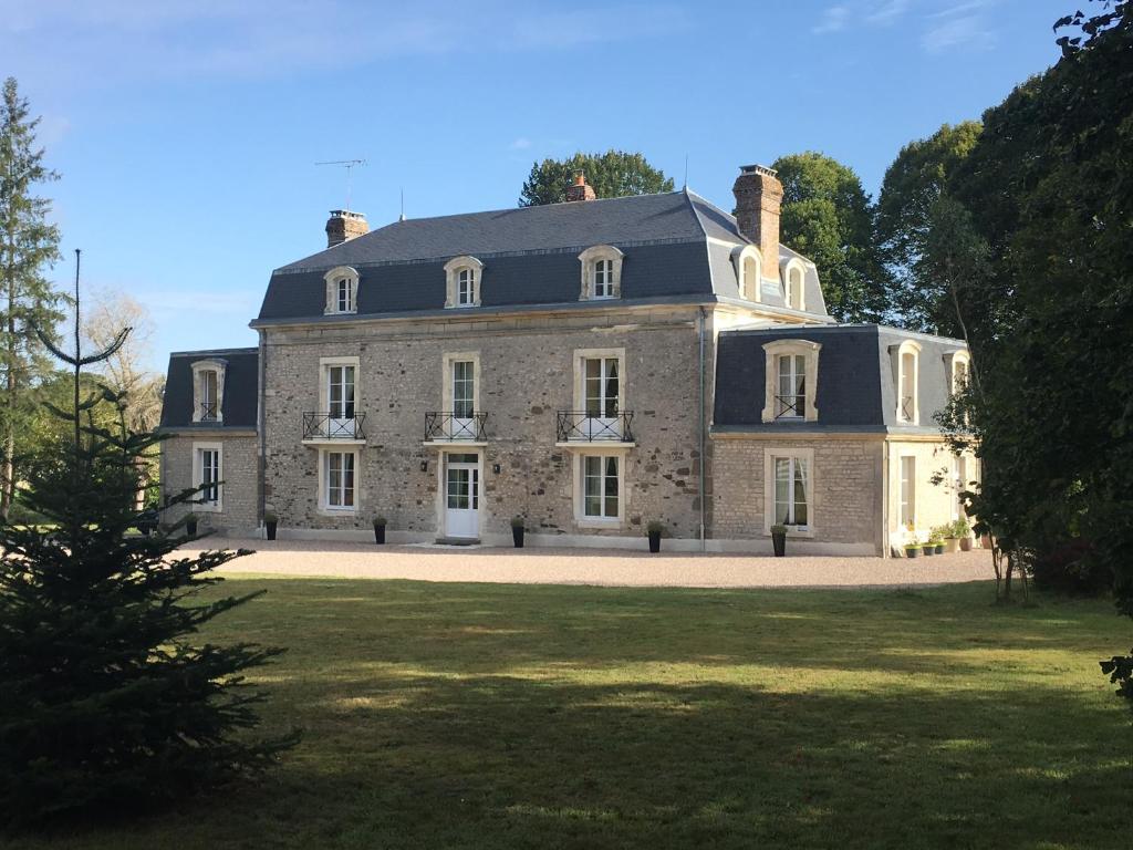 una grande casa in pietra con un ampio cortile di Le Manoir du Ribardon a Neuvy-au-Houlme