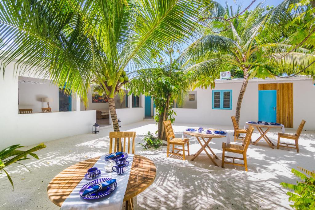 a table and chairs on the beach with palm trees at Villa Rosa Maldives in Feridhoo