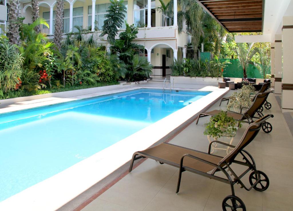 a swimming pool in a hotel with two chairs next to it at Villa Las Margaritas Caxa in Xalapa