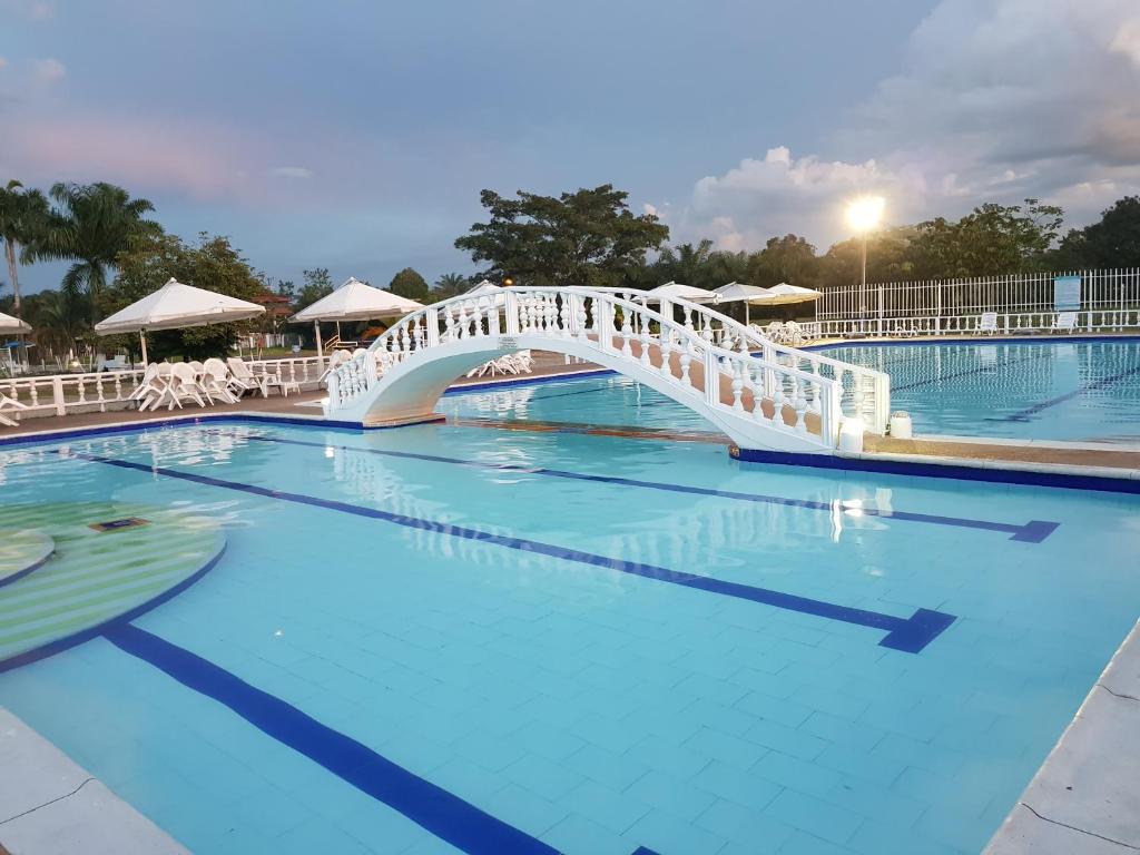 a bridge over a large pool with blue water at Hotel Campestre Kosta Azul in Villavicencio