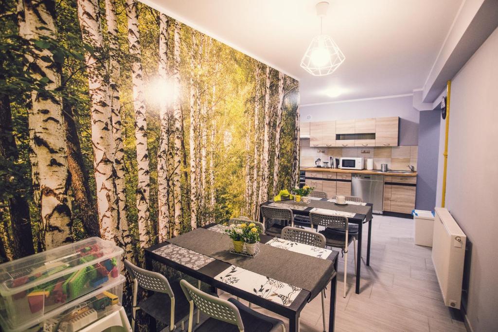 ein Esszimmer mit Tischen und einem Wandbild von Bäumen in der Unterkunft Apartament Grosik in Duszniki-Zdrój