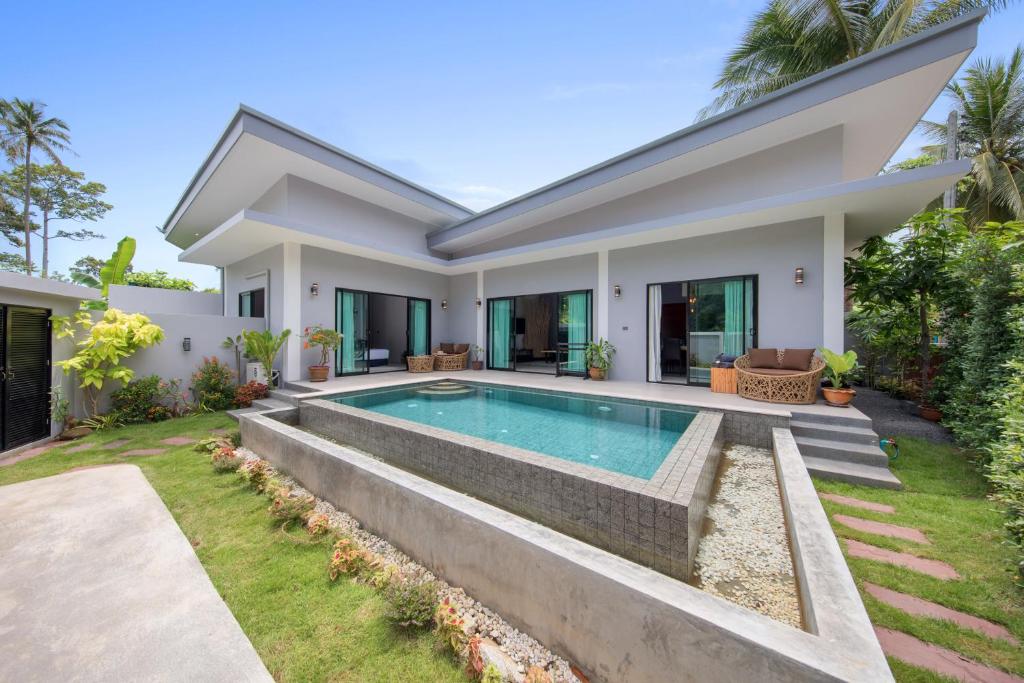 a villa with a swimming pool and a house at Baan Bua in Laem Sor