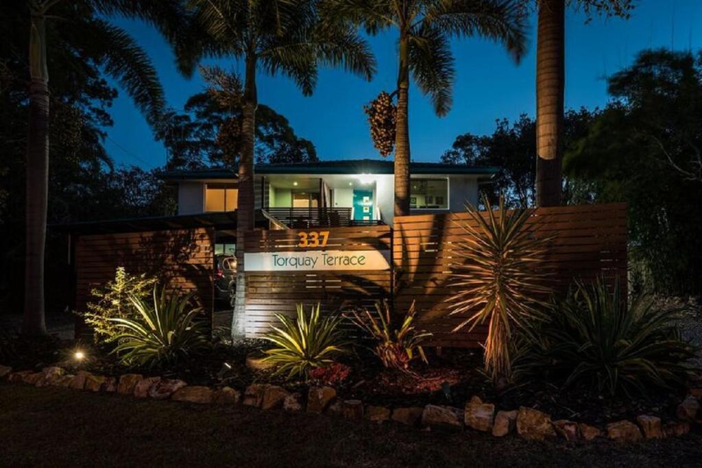 a house with palm trees in front of it at Torquay Terrace Bed & Breakfast in Hervey Bay