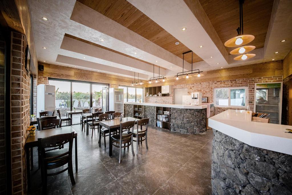 a kitchen and dining room with tables and chairs at Jeju Washington Pension in Seogwipo