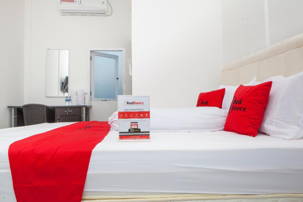 Schlafzimmer mit einem weißen Bett und roten Kissen in der Unterkunft RedDoorz near Telkom Corporate University in Bandung