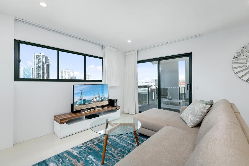 a living room with a couch and a flat screen tv at Spice Broadbeach - GCLR in Gold Coast