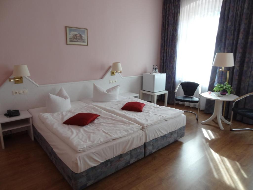 - une chambre avec un grand lit blanc et des oreillers rouges dans l'établissement Hotel Elisenhof, à Chemnitz