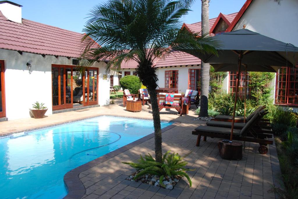 a swimming pool with a palm tree next to a house at Journey's Inn Africa Airport Lodge in Kempton Park