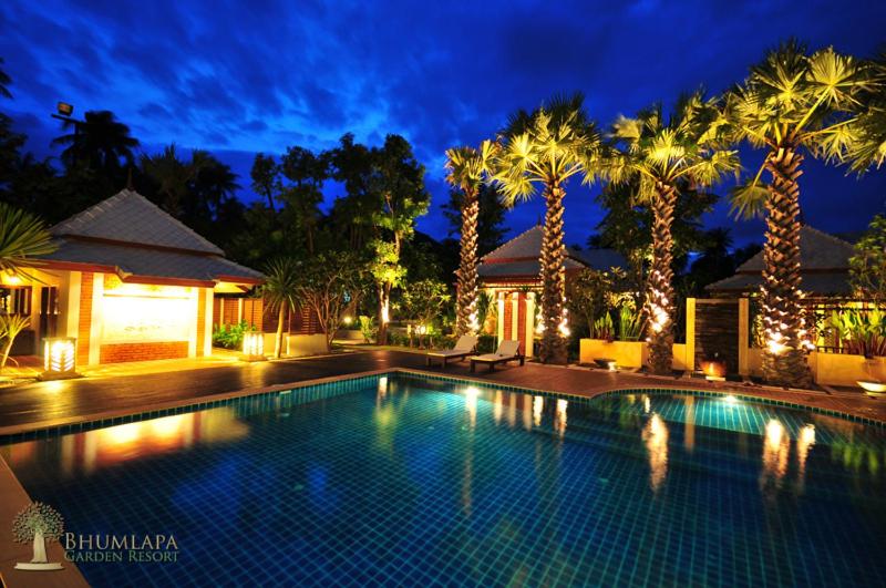 a swimming pool with palm trees at night at Bhumlapa Garden Resort in Bophut