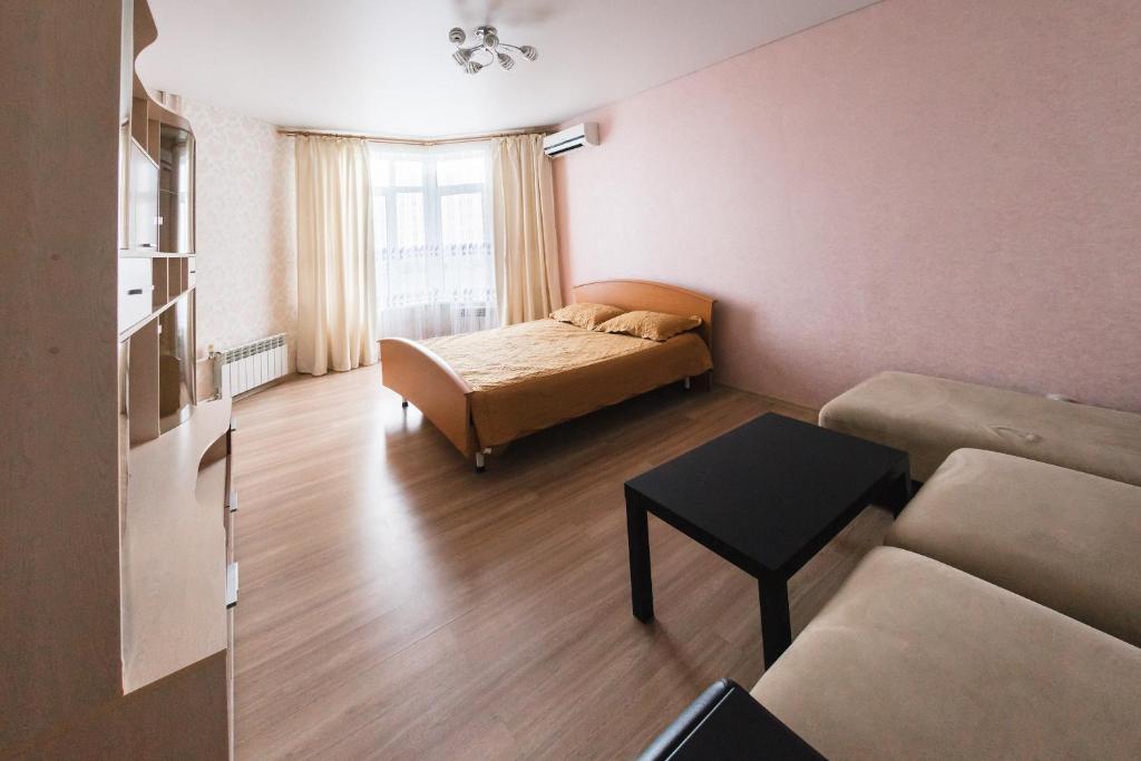 オレンブルクにあるApartment on Chkalova 51/1のベッド、ソファ、テーブルが備わる客室です。