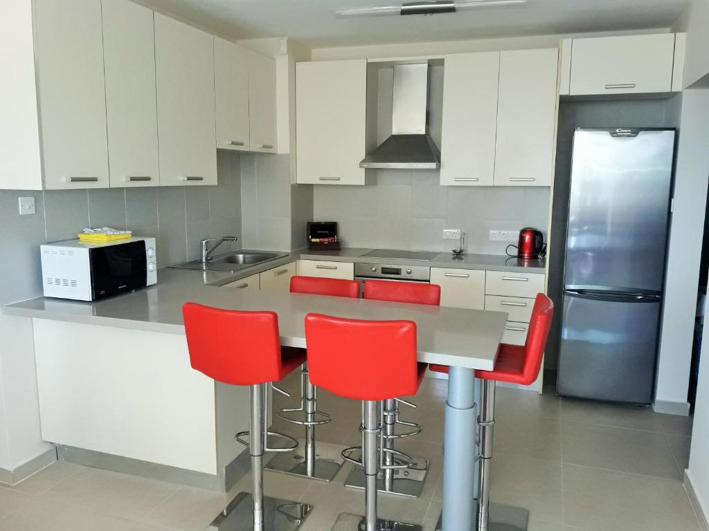 una cocina con armarios blancos y taburetes rojos en 16 SANDY BEACH en Lárnaca