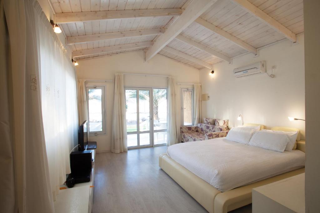 una camera da letto con un grande letto bianco e una televisione di Shkutai Hottub Arava a Ẕofar