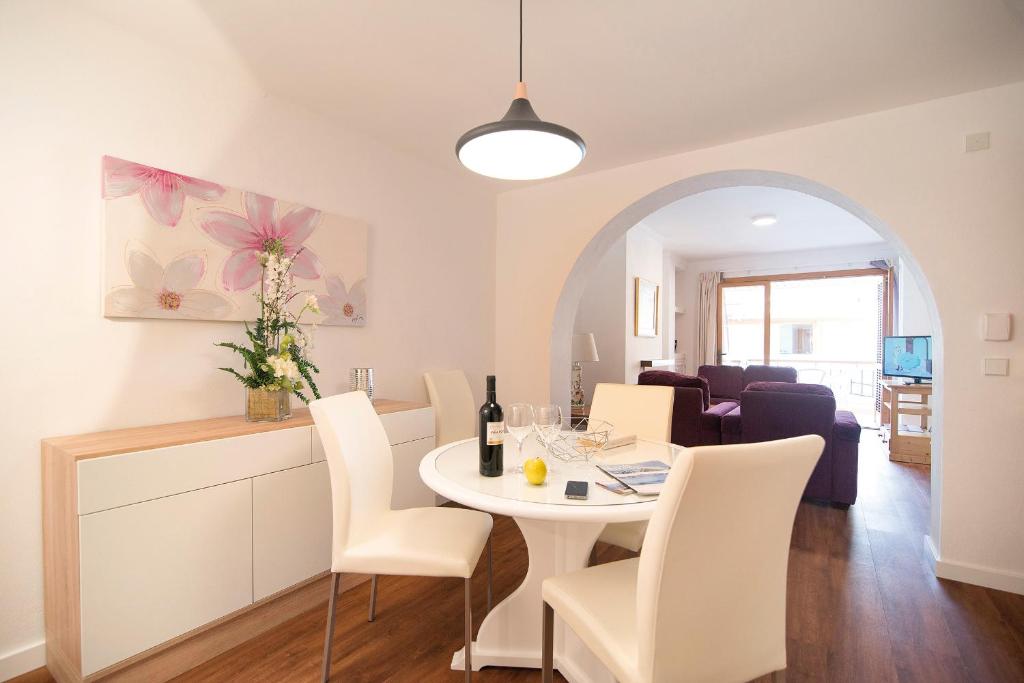 una sala da pranzo e un soggiorno con tavolo e sedie bianchi di Apartamentos Miramar a Port de Pollença