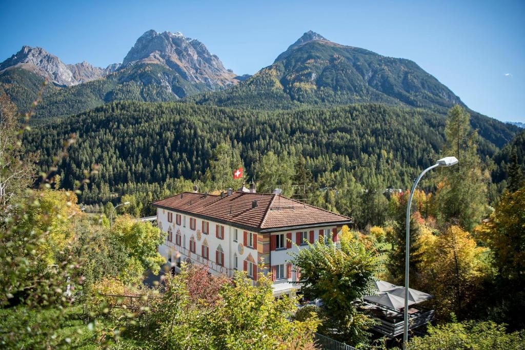 a house in the mountains with mountains in the background at Hotel Filli in Scuol