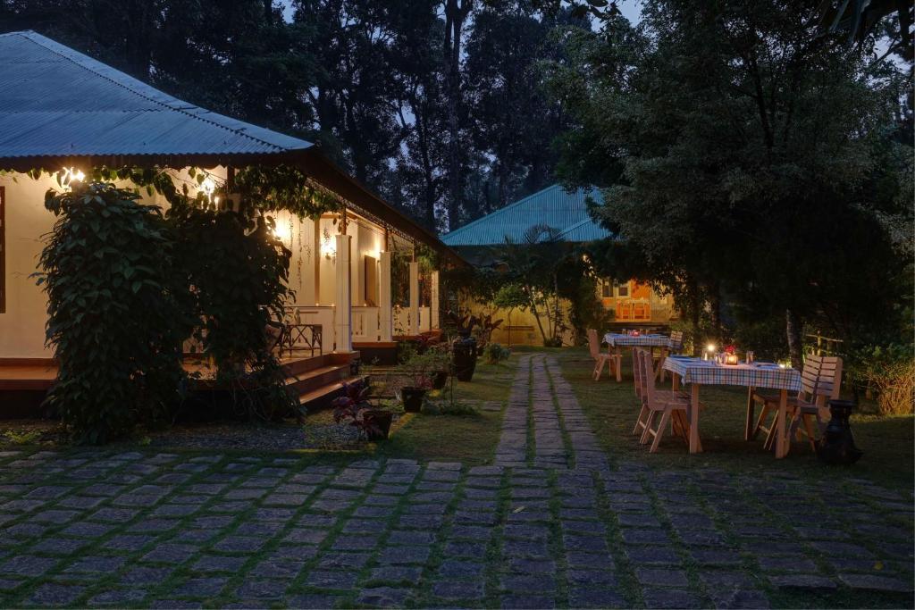 a house with a table and chairs in a yard at Dew Drops Farm Resorts in Munnar