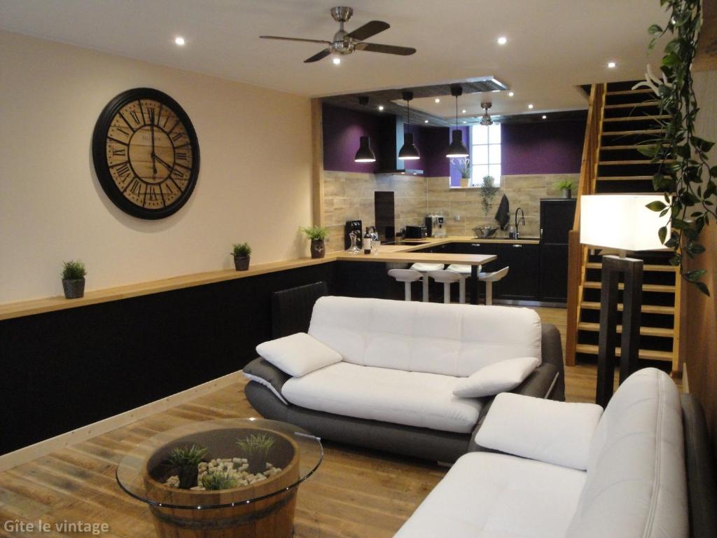 a living room with a couch and a clock on the wall at Gîte Le Vintage in Saint-Émilion