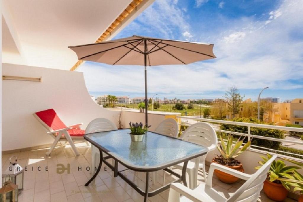 patio con mesa y sombrilla en el balcón en T1 Grevilias em Vilamoura - Greice Homes en Quarteira