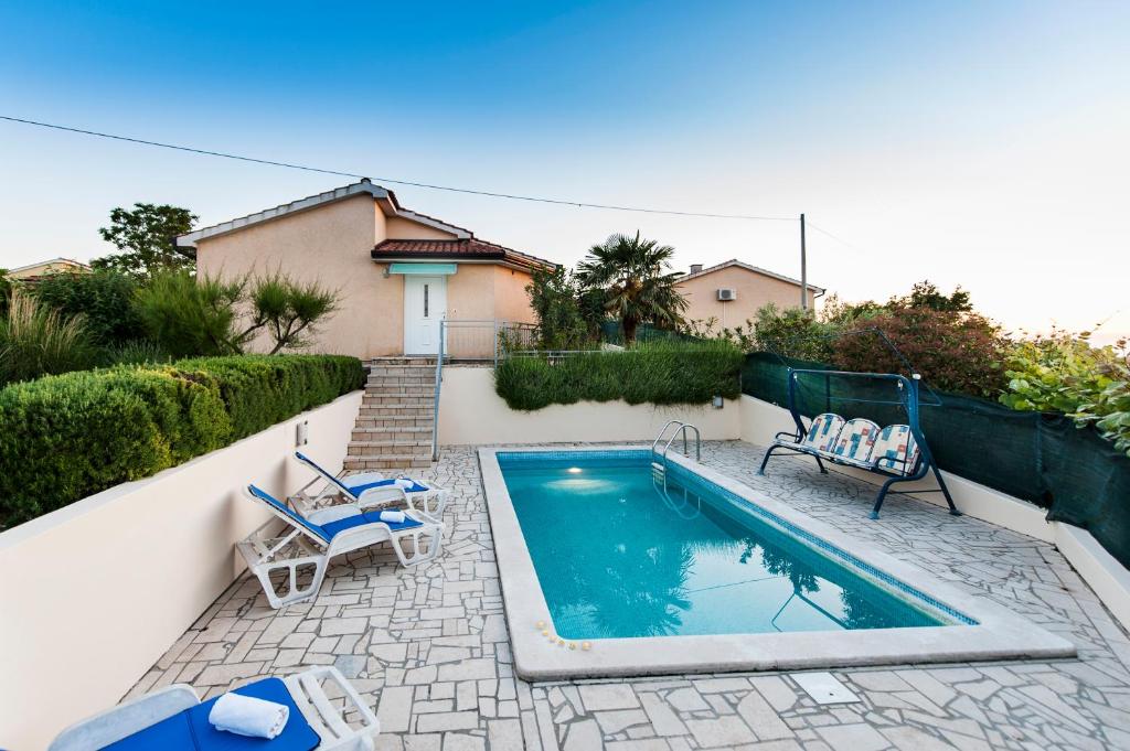 una piscina con 2 sillas azules junto a una casa en Villa Istria, en Poreč