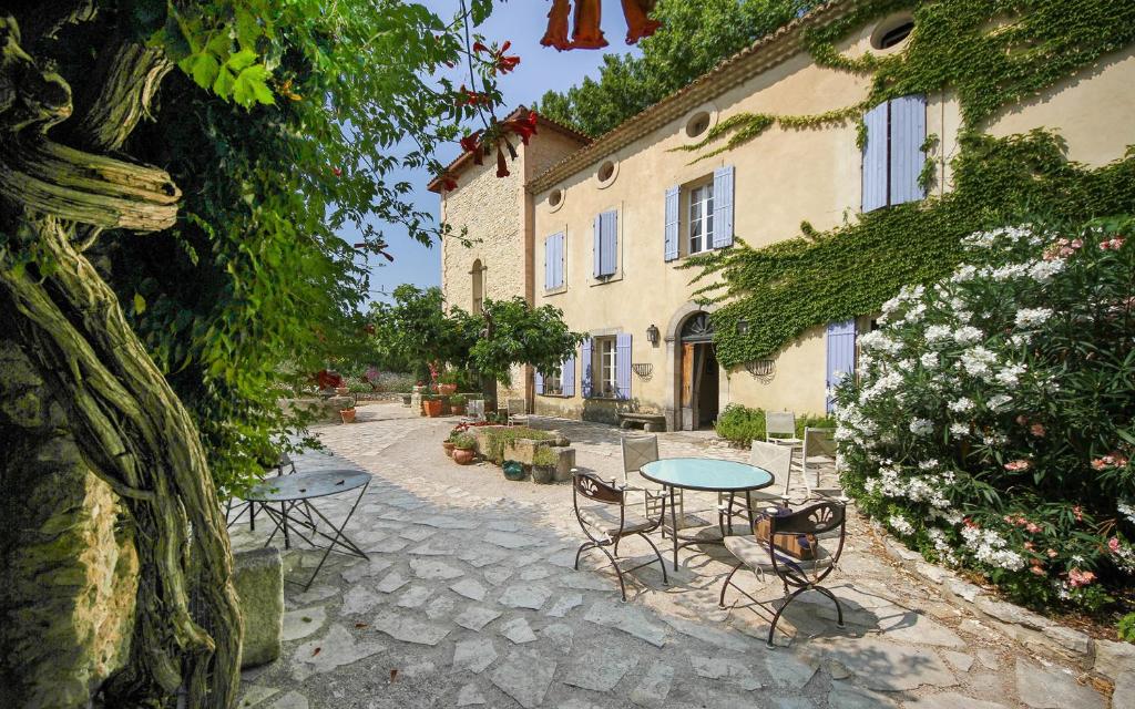 une terrasse avec une table et des chaises devant un bâtiment dans l'établissement Gite des Carmes and Spa, au Thor