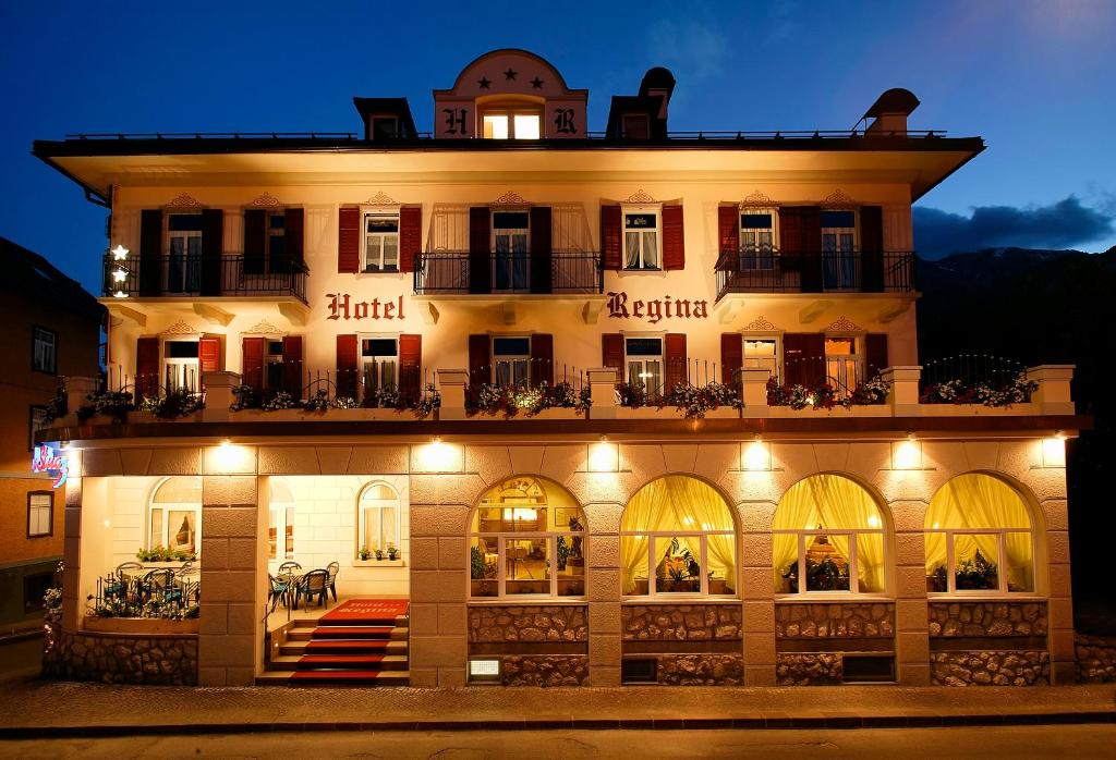 un edificio iluminado con un hotel por la noche en Hotel Regina, en Cortina dʼAmpezzo
