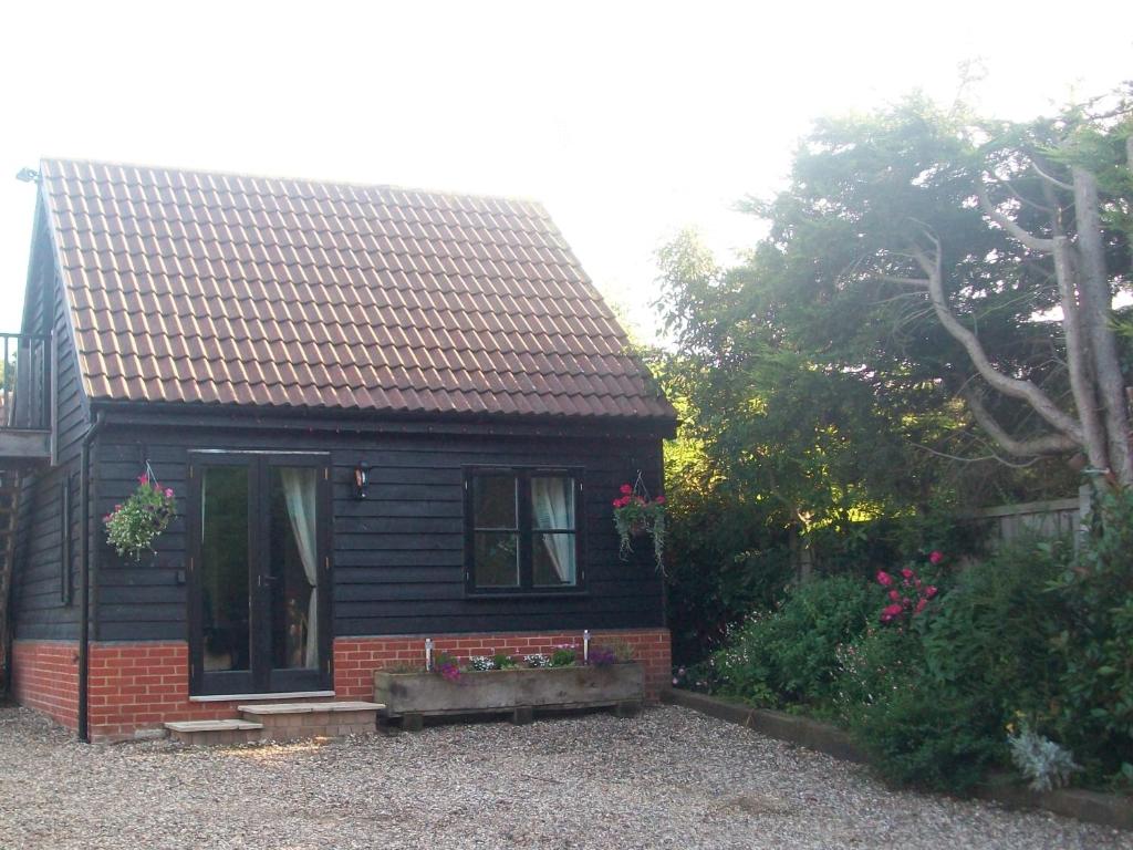 a small black house with a window in a yard at The Cartlodge B & B in Colchester