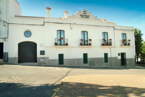 - un bâtiment blanc avec portes et fenêtres donnant sur une rue dans l'établissement Casa Rural Las Avutardas, à Sierra de Fuentes