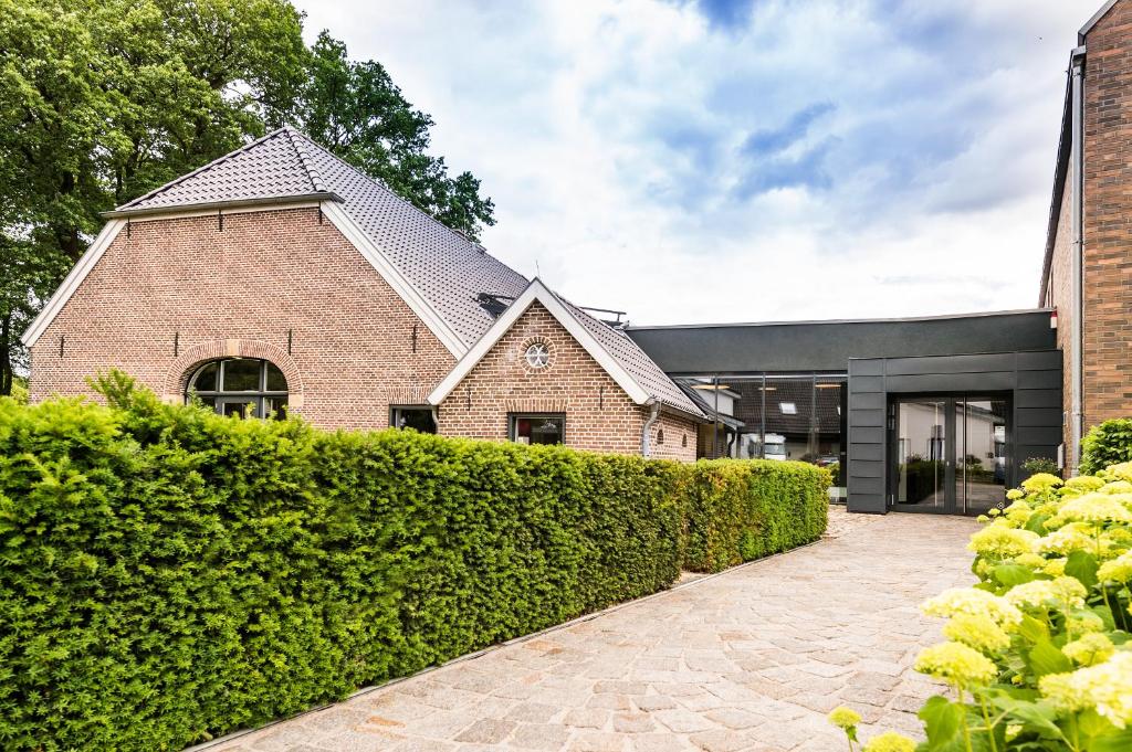 a brick house with a hedge in front of it at Hof Veldink in Emlichheim