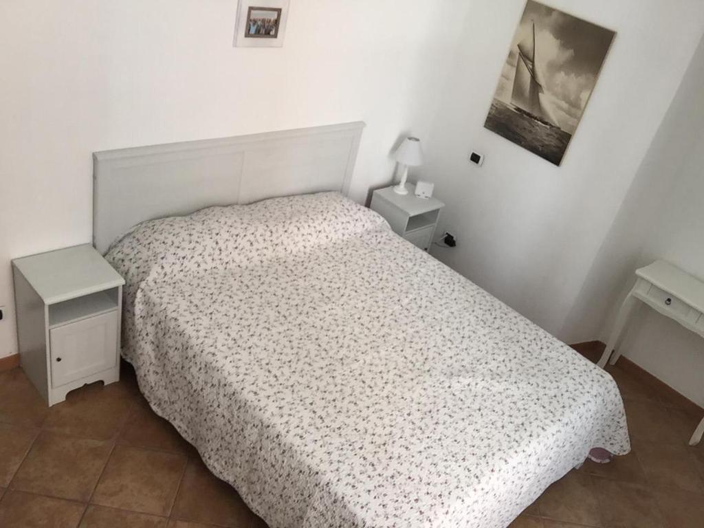 Un dormitorio con una cama blanca y dos mesitas de noche. en House of Vera, en La Spezia