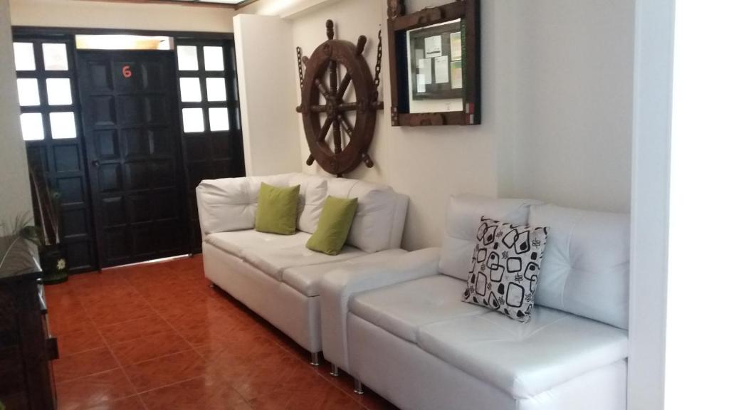 a white couch with two green pillows in a living room at La Casita in Iza