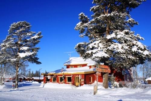 ein schneebedecktes Haus mit zwei Bäumen davor in der Unterkunft Kvanhøgd Turistsenter in Gol