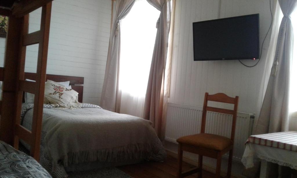 a bedroom with a bed and a television on the wall at Hostal Patrimonial Angelmó in Puerto Montt