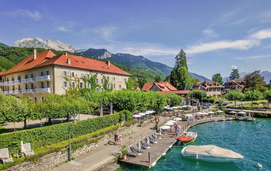 un fiume con un edificio e barche in acqua di Abbaye de Talloires a Talloires