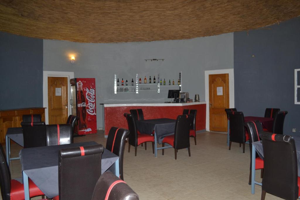 a restaurant with tables and chairs and a bar at Melia Hotel in Saly Portudal