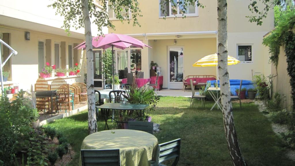 un patio con tavoli, sedie e ombrelloni di Maison Saint Louis a Paray-le-Monial